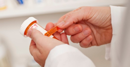 Doctor putting a label on pill bottle